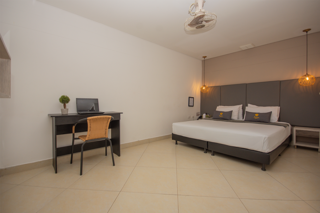 Habitación básica doble con cama doble y escritorio de trabajo junto a la ventana.