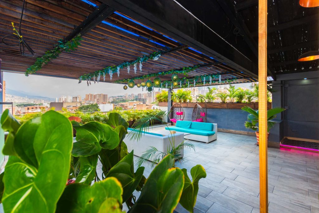 Terraza rooftop del hotel con sofás, plantas y vista panorámica de Bello.