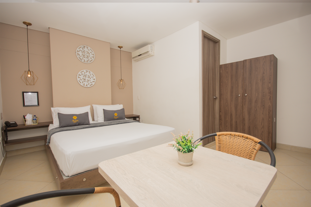 Habitación doble estándar con cama doble, mesa auxiliar y armario de madera.