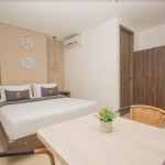 Habitación doble estándar con cama doble, mesa auxiliar y armario de madera.