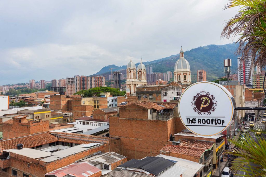 Terraza rooftop del Hotel Perlatto, con el letrero The Rooftop y vista al centro de Bello y a las cúpulas de la iglesia.