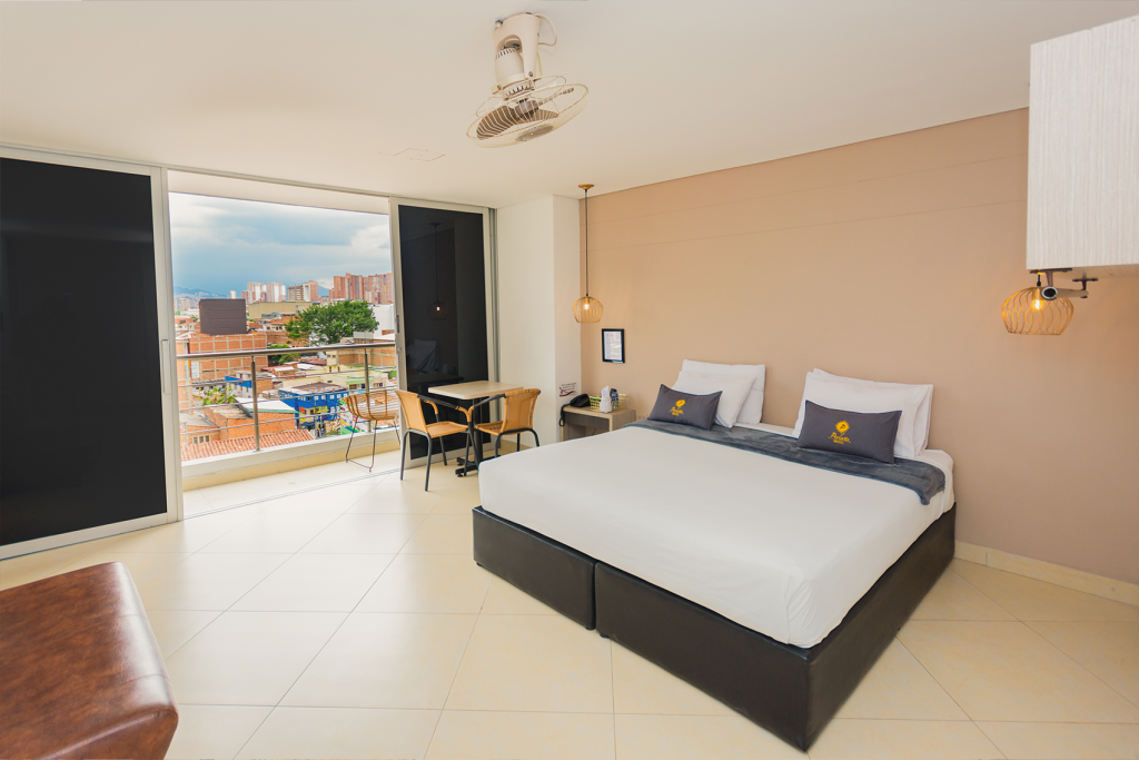 Habitación con el balcón abierto y vista a Bello desde el ventanal.