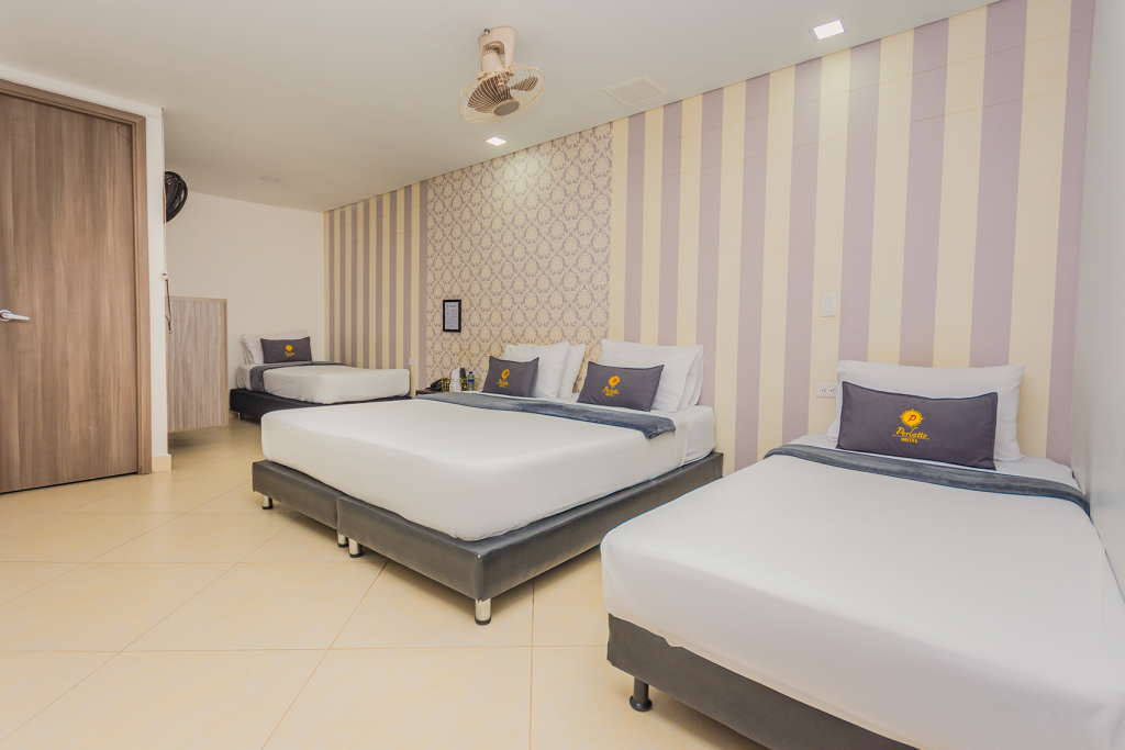 Habitación múltiple con dos camas dobles y pared empapelada a rayas.