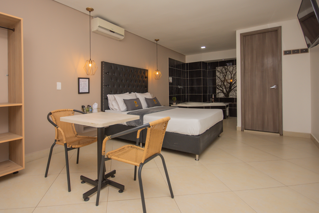 Habitación deluxe con cama doble, mesa para dos y armario de madera.