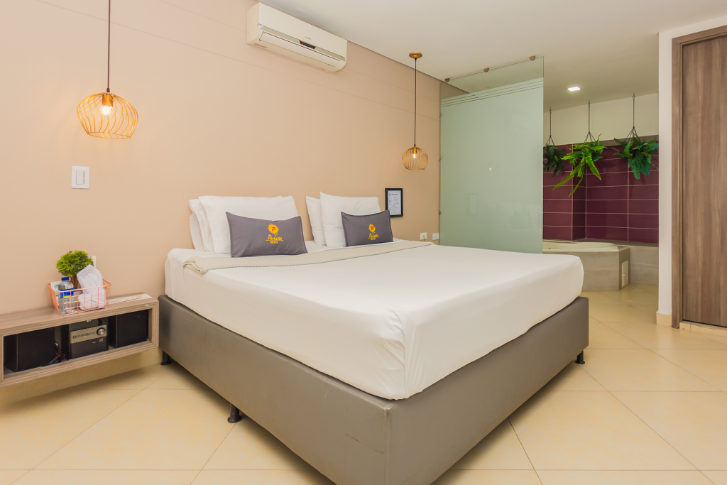 Habitación deluxe doble con cama king, lámparas colgantes y jardín vertical junto al baño.